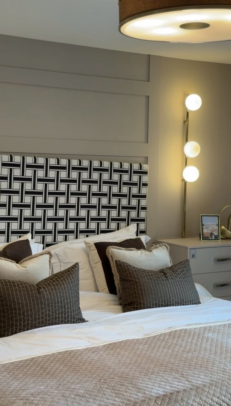 Woven monochrome headboard with brass globe wall light