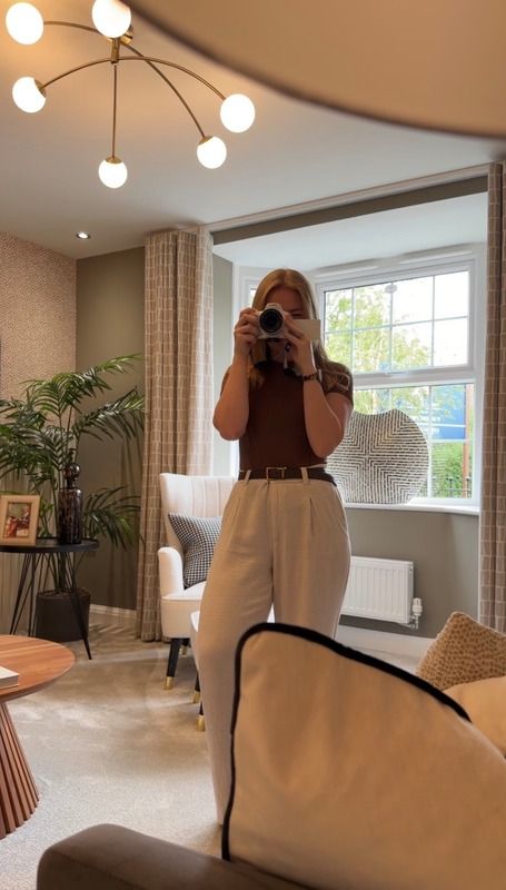 Molly filming a mirror selfie in a styled living room
