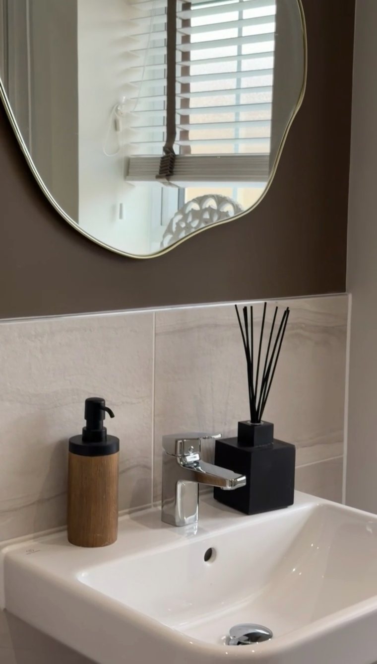 Cloakroom basin with a wavy gold mirror and black diffuser