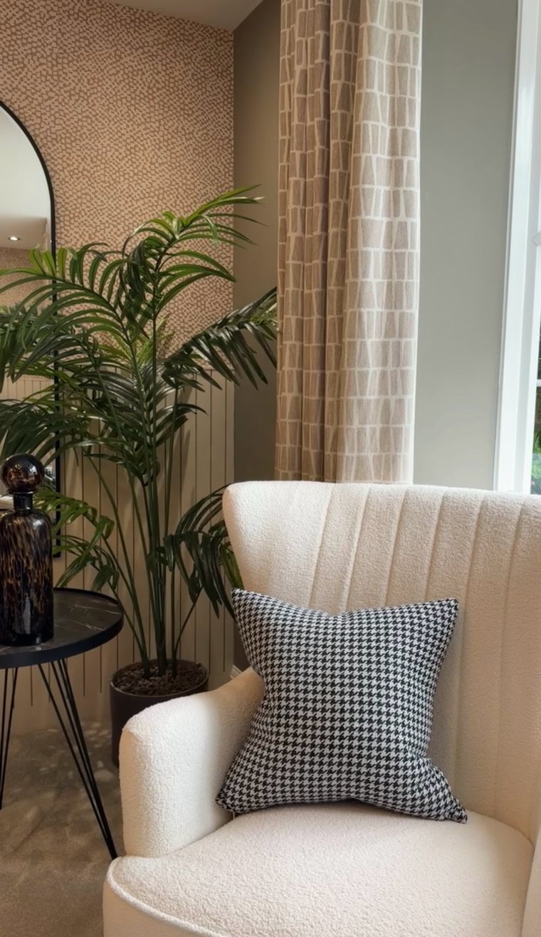 Boucle armchair with a houndstooth cushion beside a palm